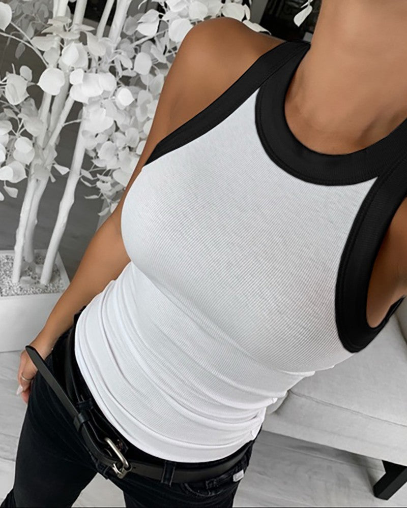 Person wearing a white tank top with black trim in an indoor setting
